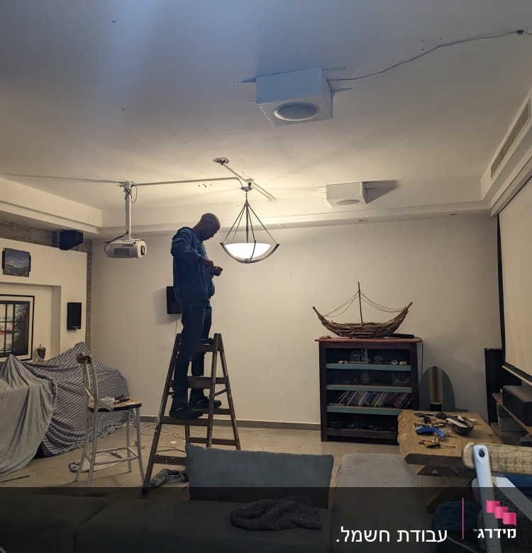 חשמלאי עומד על סולם ומתקן מנורה בתקרה